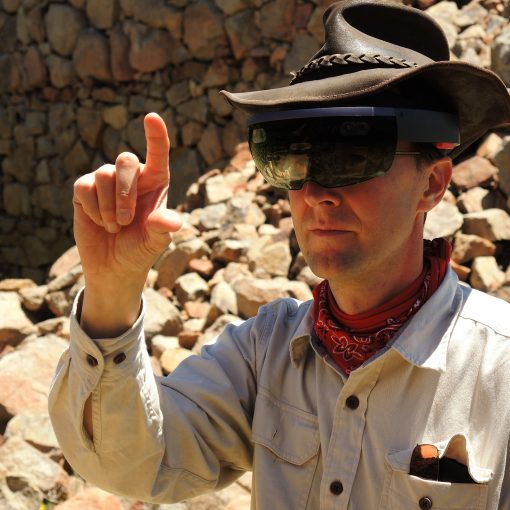 A man in a cowboy hat is pointing at rocks.