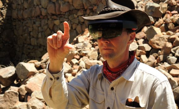 A man in a cowboy hat is pointing at rocks.