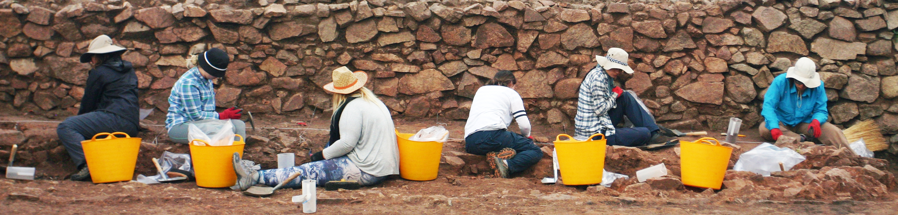 A group of people sitting on a stone wall.
