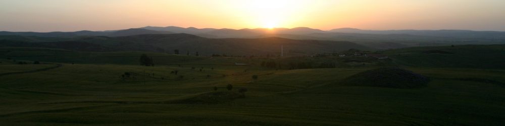 A sunset over a green field.