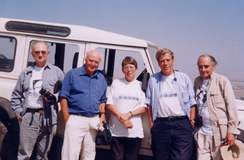 A group of people standing in front of a white vehicle.