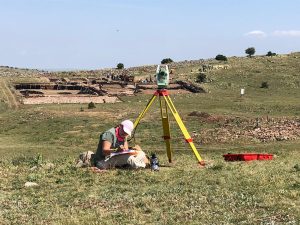 A woman is using a surveying equipment in a field.