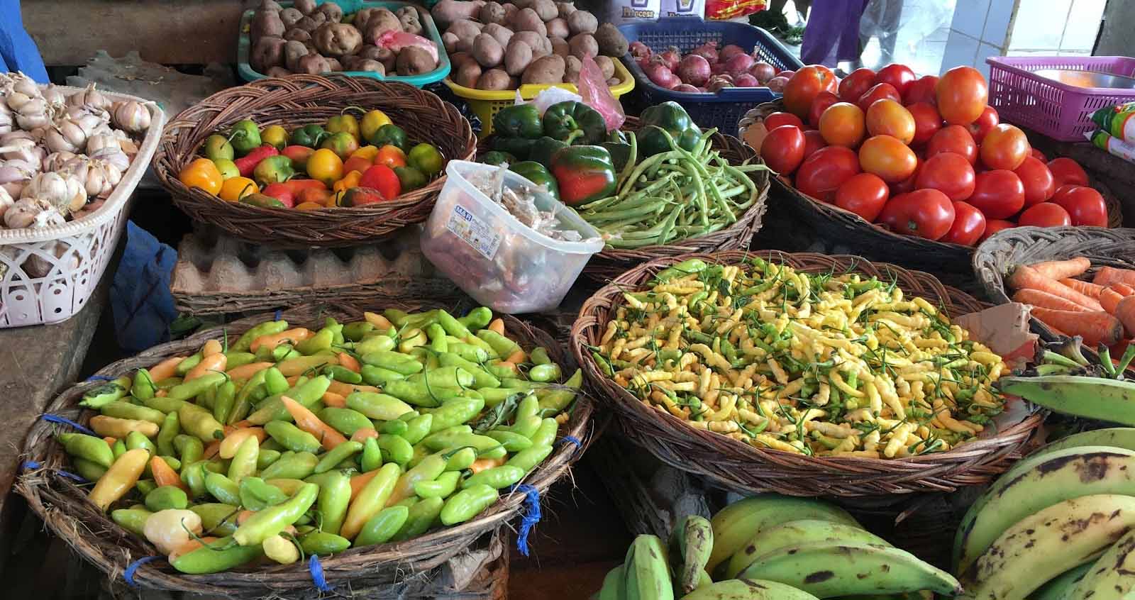 Assorted fresh vegetables and fruits displayed in baskets at a market stall.