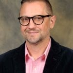 A man wearing glasses and a pink shirt.