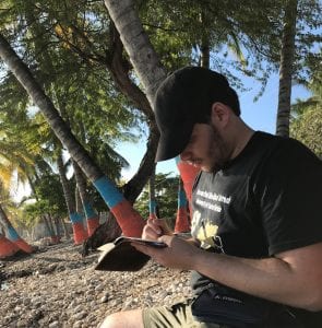 Person sitting on a beach writing in a journal