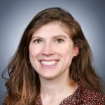 A smiling woman in a floral shirt.