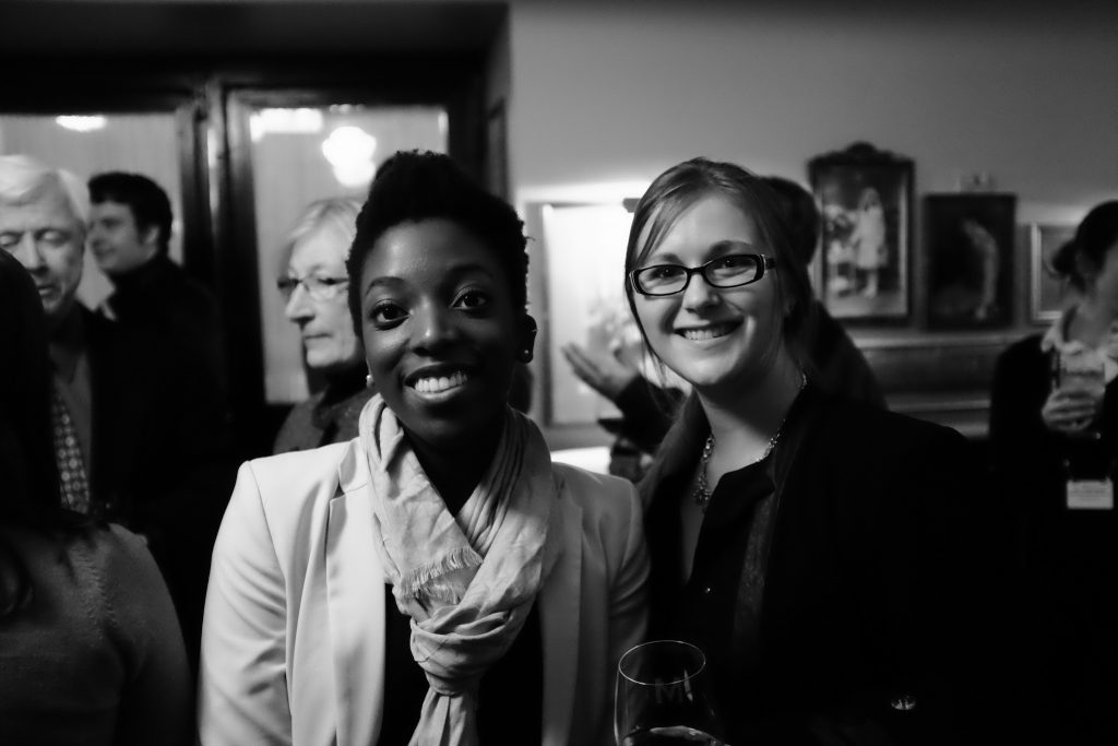 Two women smiling at a social event.