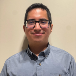 Julio Man with glasses wearing a blue shirt smiling at the camera.