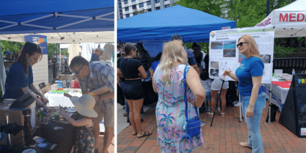 People interacting at outdoor booths during a community event, with informational displays and promotional materials under blue canopies.