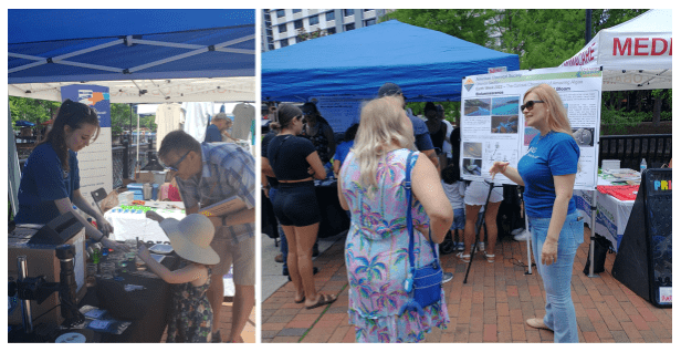 People are interacting at an outdoor informational event with booths and displays under blue canopies. Some are engaging with exhibitors, while others are observing posters and materials.
