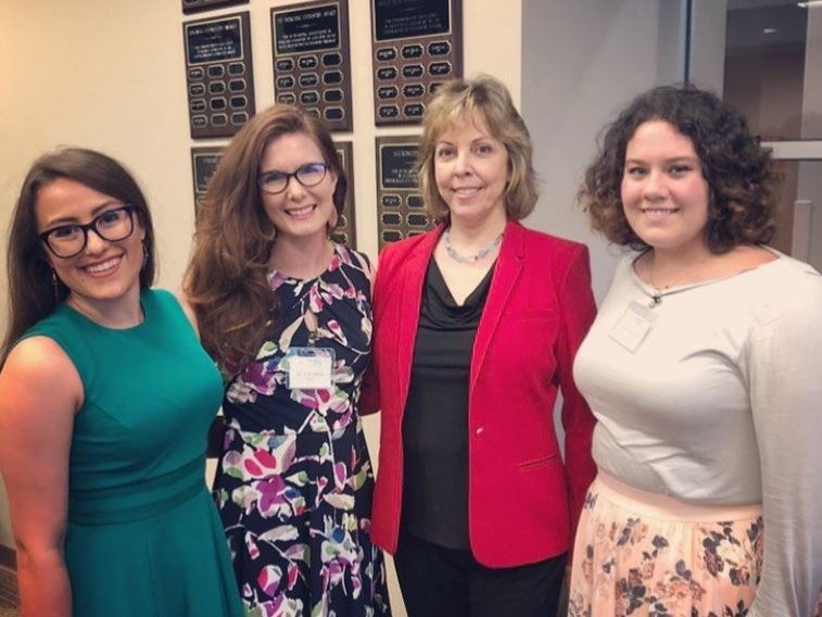 Four women posing for a photo in an office.