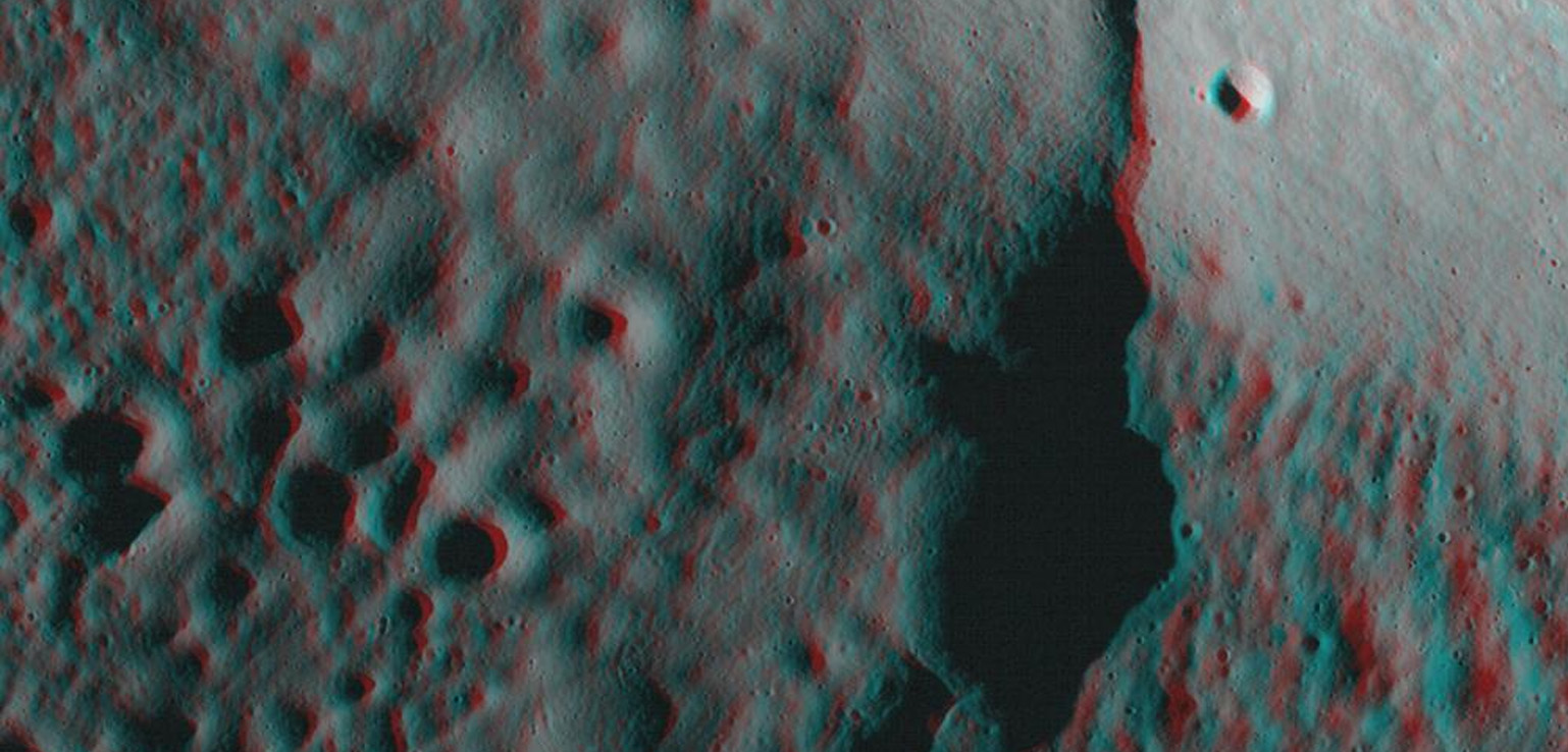 Anaglyph image showing a rough, cratered surface with varying depths and elevations, revealing a landscape possibly resembling the moon or another celestial body.