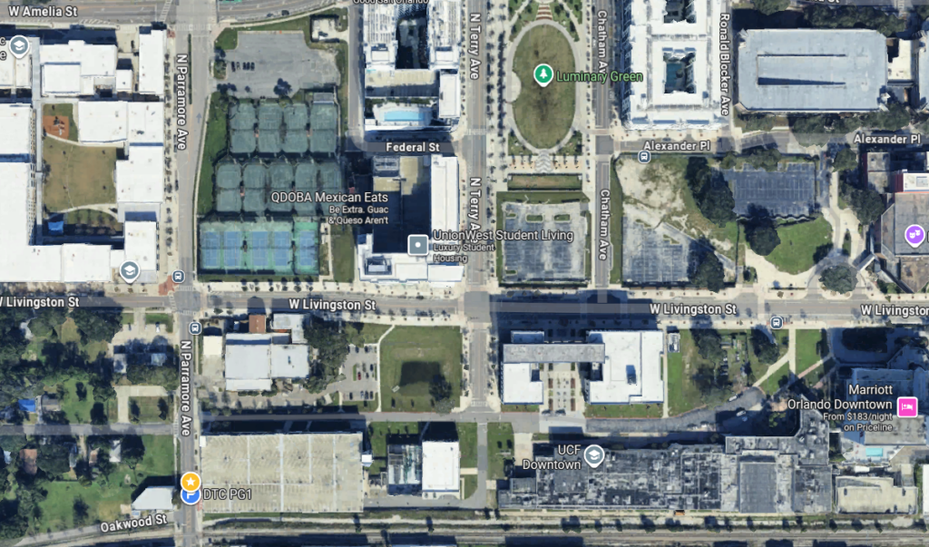 Aerial view of a city block showing streets, buildings, parking lots, and labeled locations such as QDOBA Mexican Eats, Luminary Green, and Oakwood St. Intersection at W Livingston St visible.