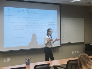 A person stands in front of a projector screen giving a math lecture on bijective proofs in a classroom setting.