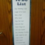 A "to do list" sign hanging on a wooden door, featuring humorous tasks like "cry (standing up)," and "get a bird.