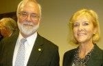 Two smiling adults, a man with a beard and a woman with blonde hair, standing in a room at a formal event.