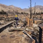 An investigator searches the Oakridge mobile home community which was devastated by a wildfire in the Sylmar area of Los Angeles