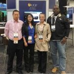 Four people standing at a ucf statistics data mining conference booth, wearing conference badges and smiling at the camera.
