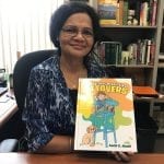 A woman in an office holding a children's book titled