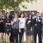 Group of diverse professionals posing together with drinks at an outdoor networking event.