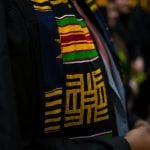 Close-up of a graduation stole with traditional african kente cloth patterns, worn over a black gown.