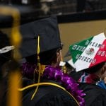Graduates in caps at ceremony, one cap decorated with "dreams without borders" and a globe, symbolizing aspirations and global outlook.