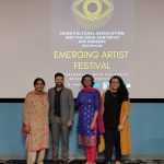 Four people standing in front of a promotional banner for the 2nd annual emerging artist festival at ucf.