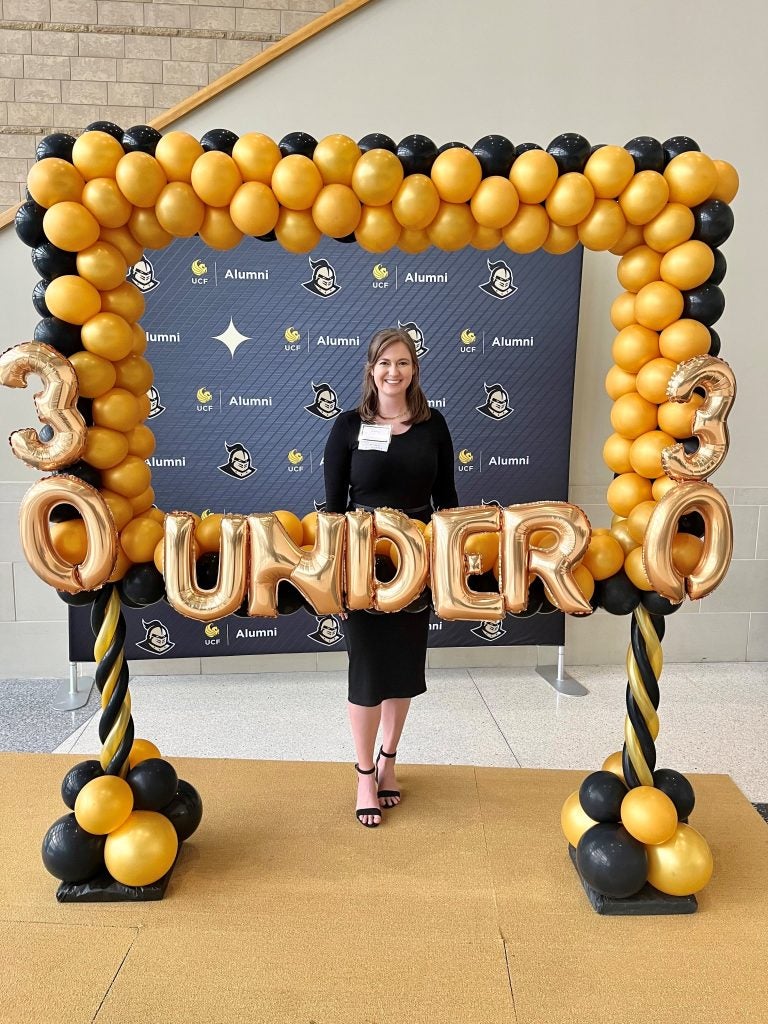 Alanna Reynolds standing behind gold balloons