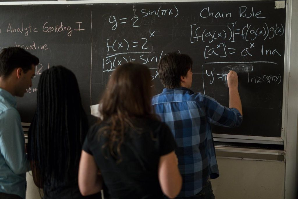Mathematics students doing equations on whiteboard 