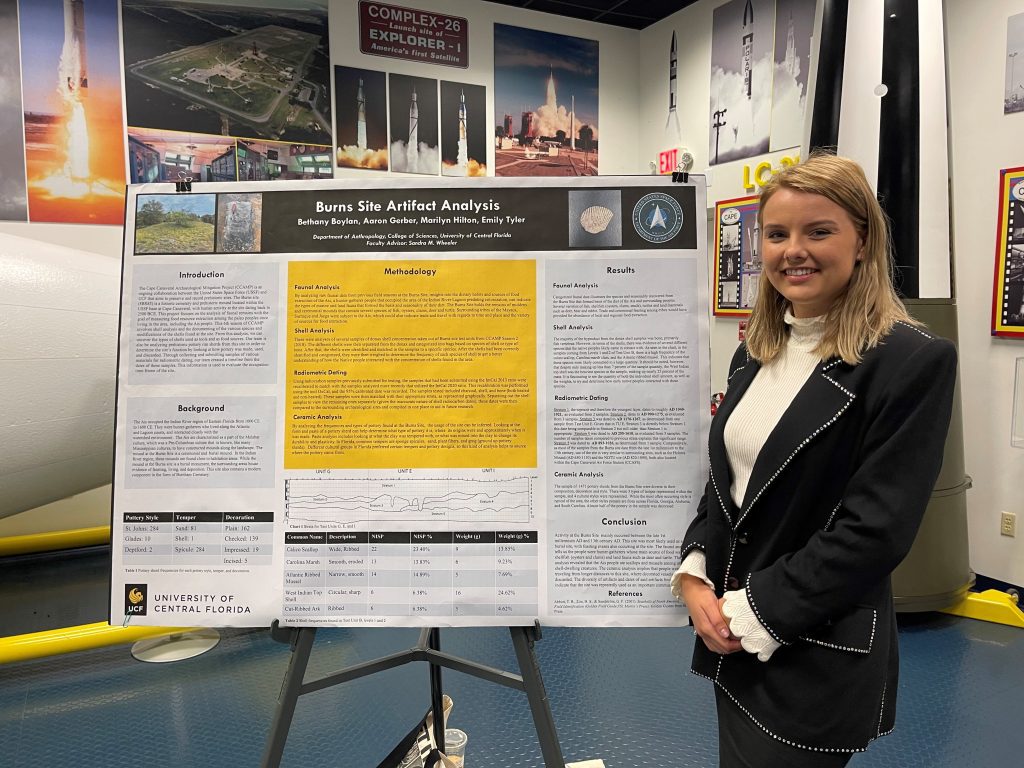 Anthropology student Emily Tyler standing by research poster