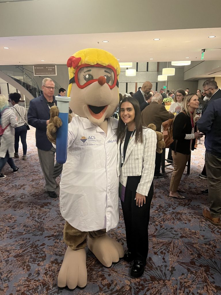 A woman posing with a mascot at an event.