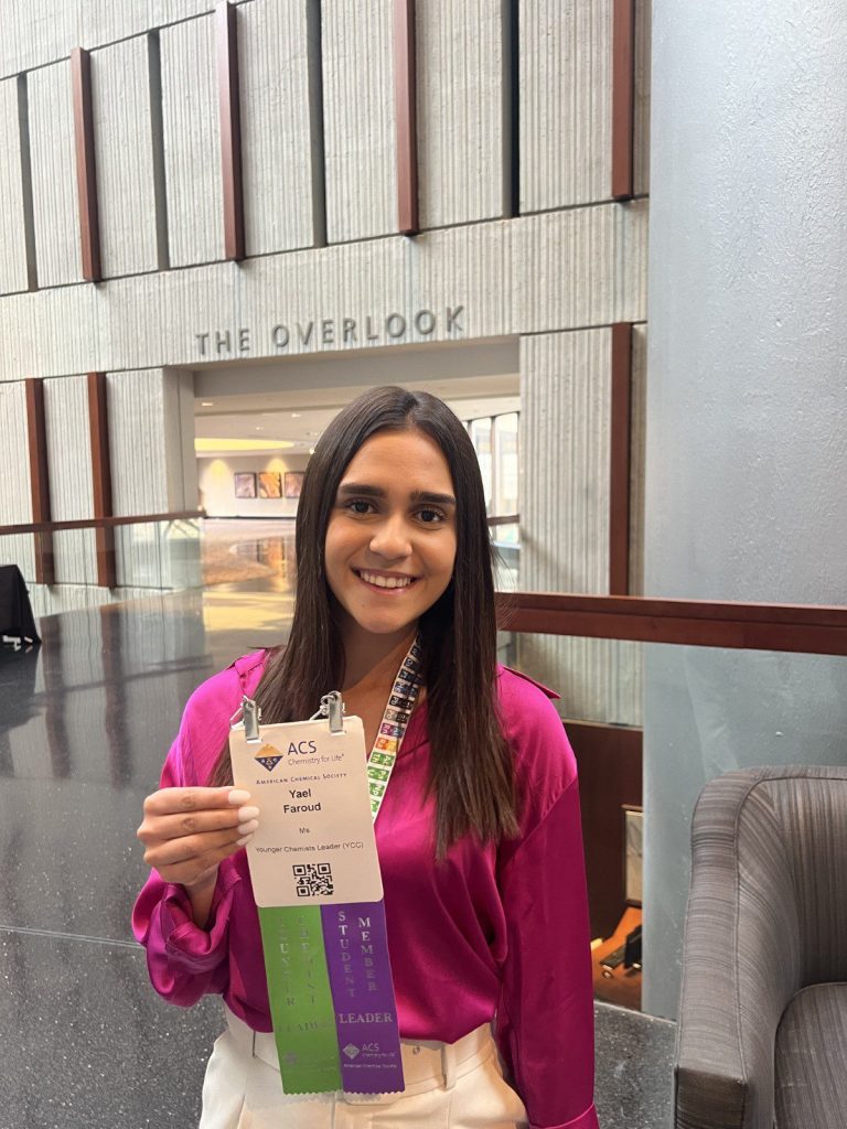 A young woman holding a certificate in a lobby.