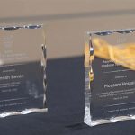Two acrylic awards on a table, one reading 