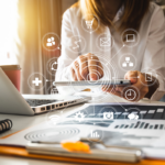 Person using a tablet at a desk with documents and charts, overlaid with digital network and technology icons representing various online services and connectivity.