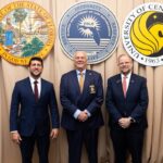 Three men in suits stand in front of official seals for the State of Florida, Florida Department of Law Enforcement, and University of Central Florida.