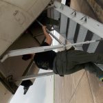 Person in casual clothing climbing up the stairs into an aircraft.