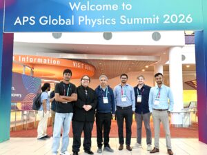 Six people stand beneath a sign reading "Welcome to APS Global Physics Summit 2026" in a convention center lobby.