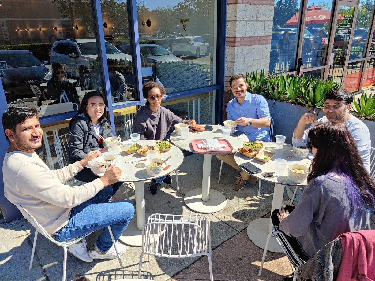 Five people eating lunch outside a restaurant on a sunny day