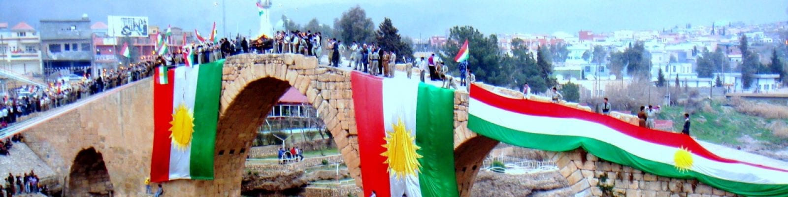 A group of people are standing on a bridge with flags.