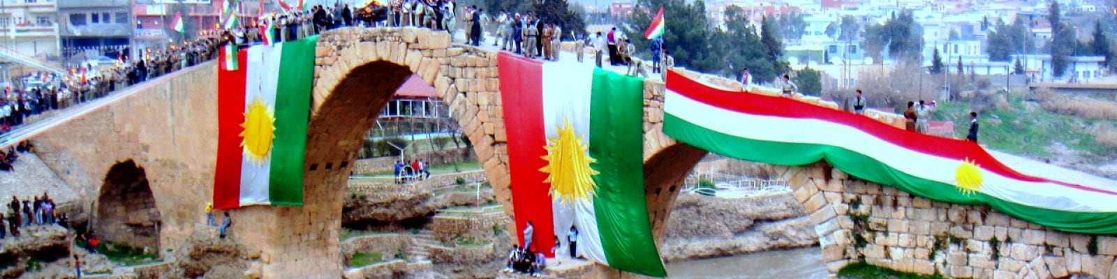 A group of people are standing on a bridge over a river.