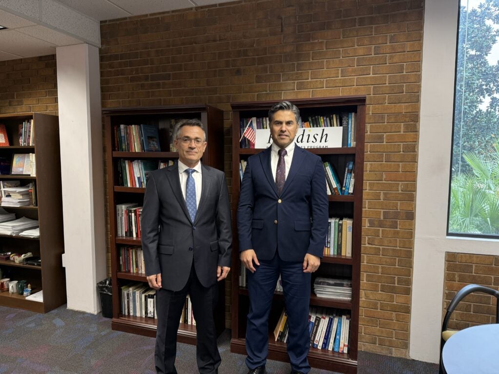 Two men in suits standing in front of bookshelves.