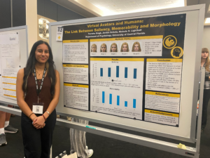 A woman stands next to a research poster titled "Virtual Avatars and Humans: The Link Between Saliency, Memorability and Morphology" at an academic conference.