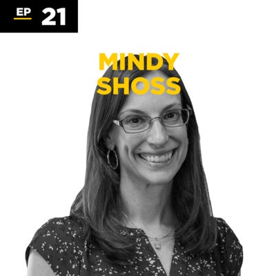 Black and white portrait of a woman with long hair and glasses, smiling. Text reads "EP 21" and "MINDY SHOSS" in bold yellow letters above her head.