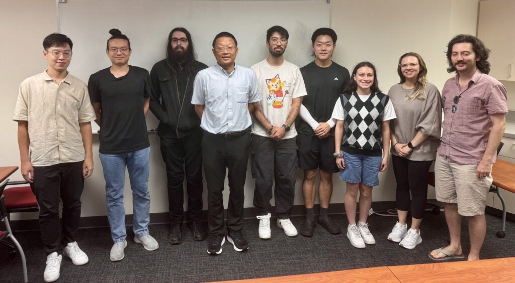 Dr. Huang standing with his eight supervised students.