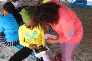 Two undergraduate students in Belize assemble a drone in the field to map a nearby island as part of their summer fieldwork experience.