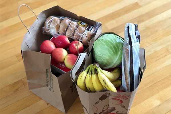 Two brown paper bags filled with fruit and vegetables.