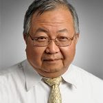 An asian man wearing glasses and a yellow tie.